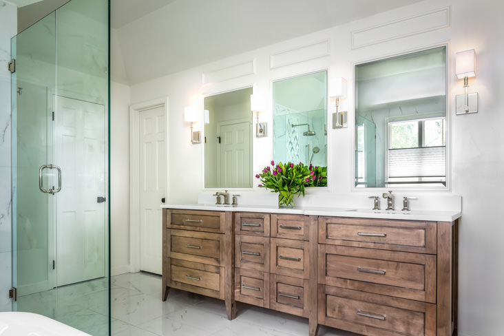 The custom cabinetry and light sconces are one of the many outstanding design features of this master bathroom